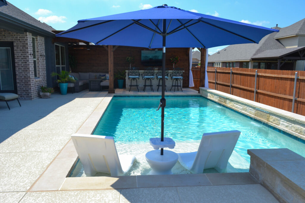 Safe, long lasting custom pool after soil injections completed with umbrella and lounge chairs.