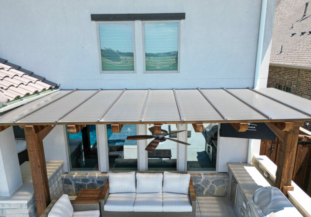 pergola cover system attached to a home with white furniture and a ceiling fan.