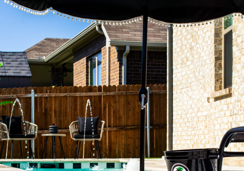Custom plunge pool in a small backyard with fountains and umbrella.